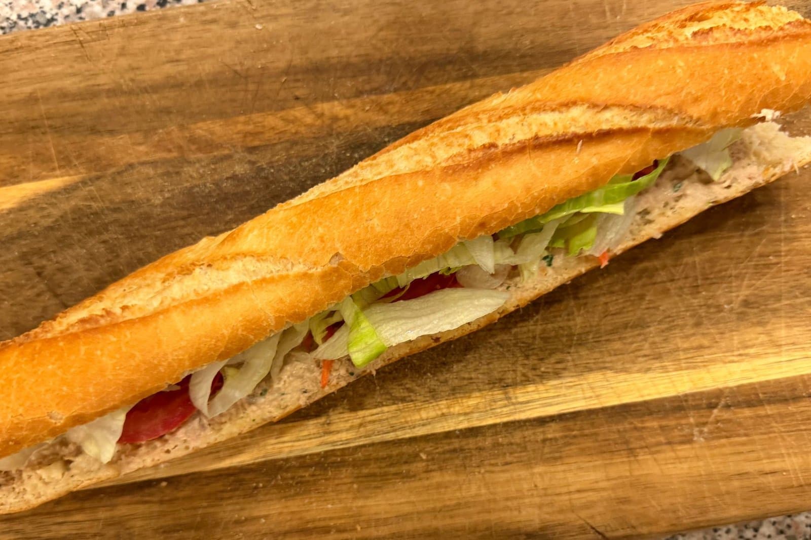 Une baguette garnie, ouverte sur une planche en bois